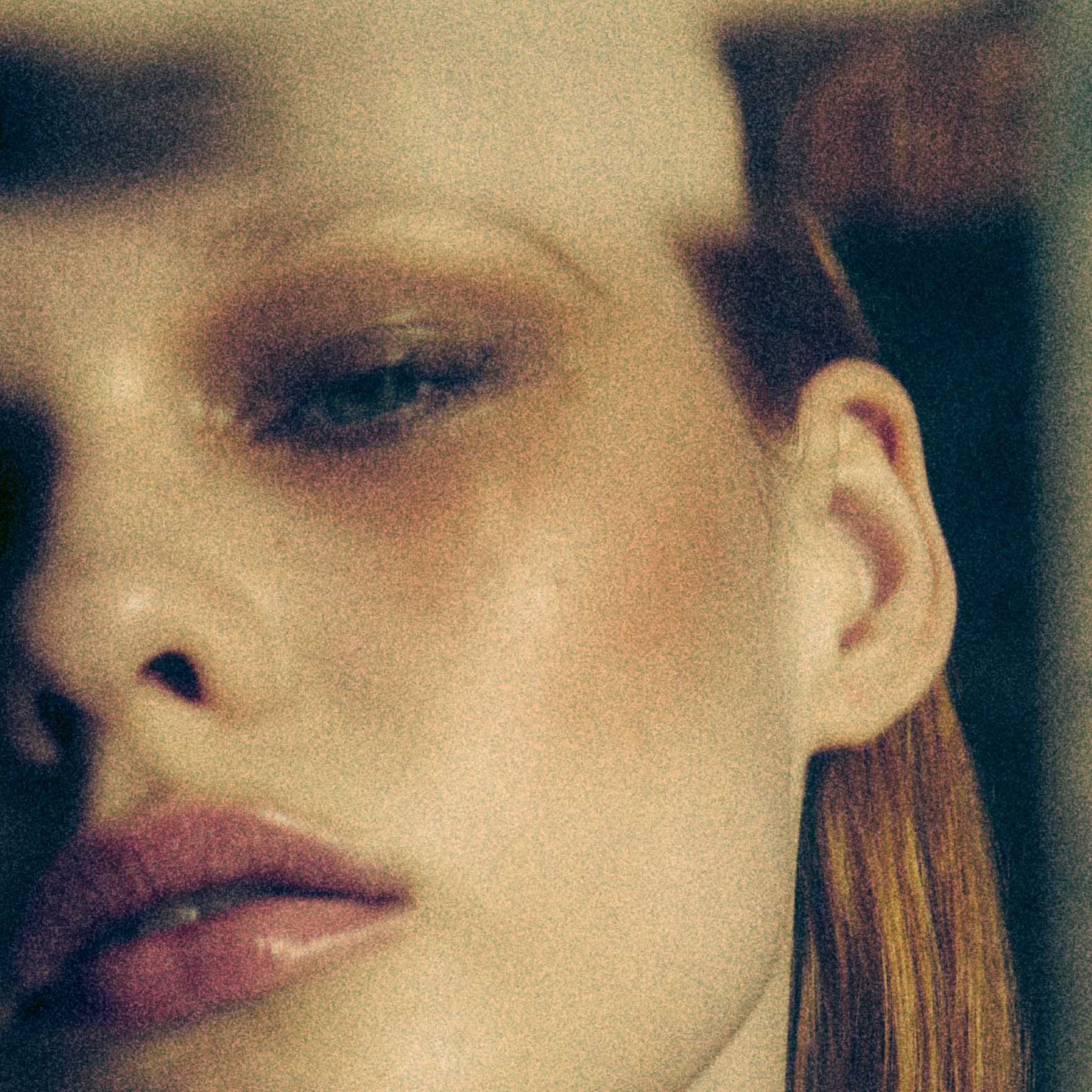 Macro underwater portrait focusing on a model's face, features, and wet hair with a warm, grainy, and textured fine art aesthetic by photographer Claudia Legge.